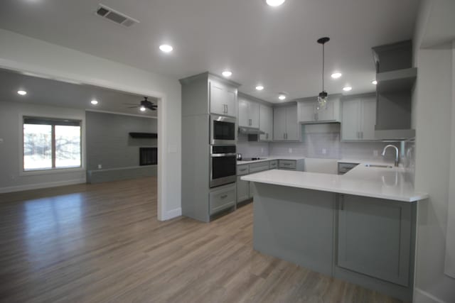 kitchen with visible vents, appliances with stainless steel finishes, wood finished floors, a peninsula, and gray cabinetry