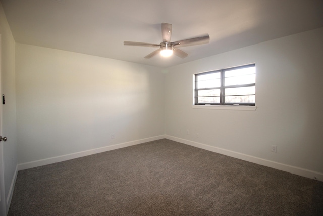 spare room with dark colored carpet, ceiling fan, and baseboards