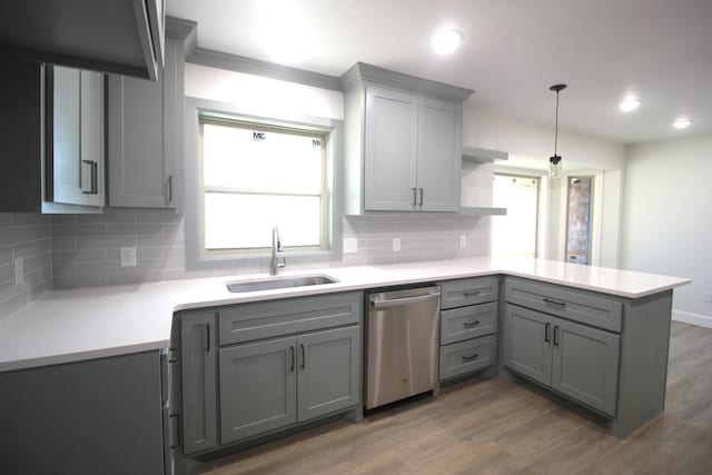 kitchen with dishwasher, a peninsula, a sink, and gray cabinetry