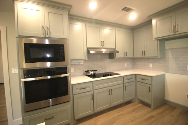 kitchen featuring under cabinet range hood, gray cabinets, stainless steel appliances, and light wood-style floors