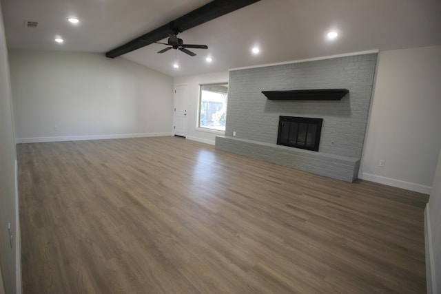 unfurnished living room featuring lofted ceiling with beams, a fireplace, wood finished floors, and baseboards