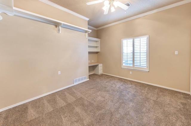 spare room with crown molding, ceiling fan, carpet, built in desk, and a textured ceiling