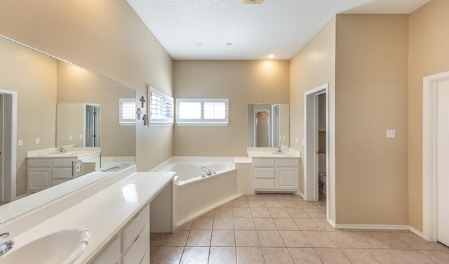 bathroom featuring a washtub, vanity, a textured ceiling, tile patterned floors, and toilet