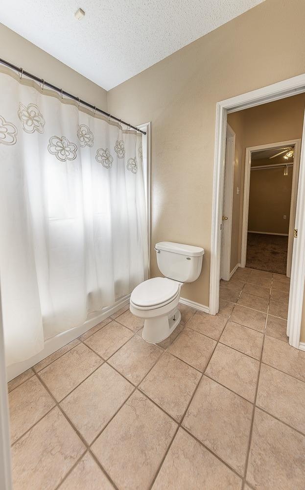 bathroom featuring tile patterned flooring, a textured ceiling, and toilet