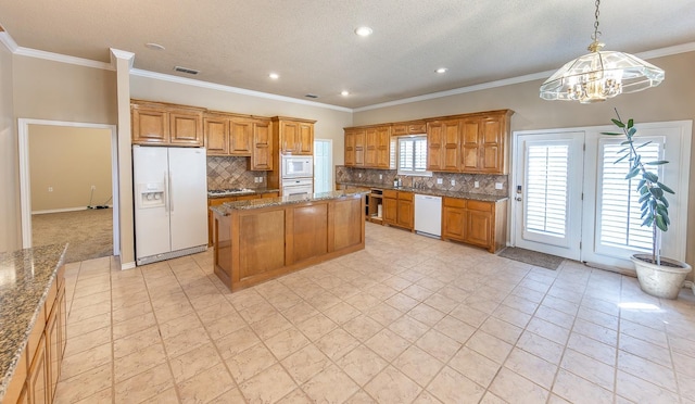 kitchen with stone countertops, backsplash, hanging light fixtures, a center island, and white appliances