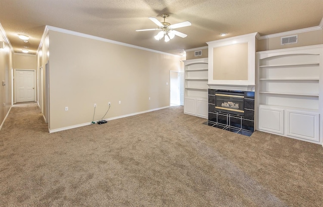 unfurnished living room with a tiled fireplace, carpet, ceiling fan, crown molding, and a textured ceiling