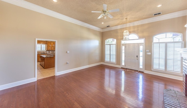 foyer featuring a healthy amount of sunlight, ornamental molding, wood-type flooring, and ceiling fan