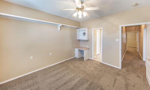 unfurnished bedroom with ceiling fan, light colored carpet, and a textured ceiling