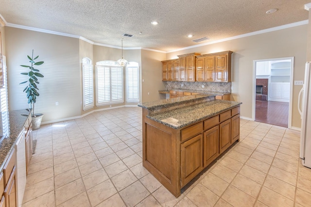 kitchen with dark stone countertops, backsplash, hanging light fixtures, a center island, and ornamental molding