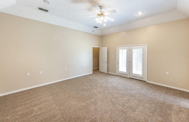 carpeted spare room featuring ceiling fan, vaulted ceiling, and a textured ceiling