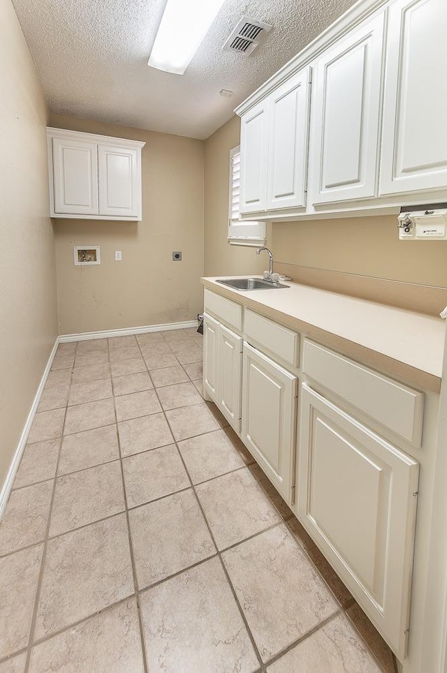 laundry room featuring light tile patterned flooring, sink, cabinets, washer hookup, and a textured ceiling