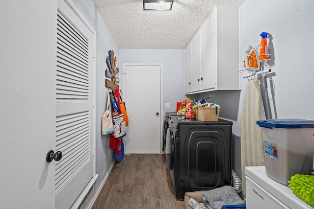 laundry room featuring cabinets, washing machine and clothes dryer, a textured ceiling, and light hardwood / wood-style flooring