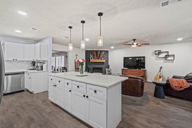 kitchen with pendant lighting, dishwasher, wood-type flooring, white cabinets, and a kitchen island