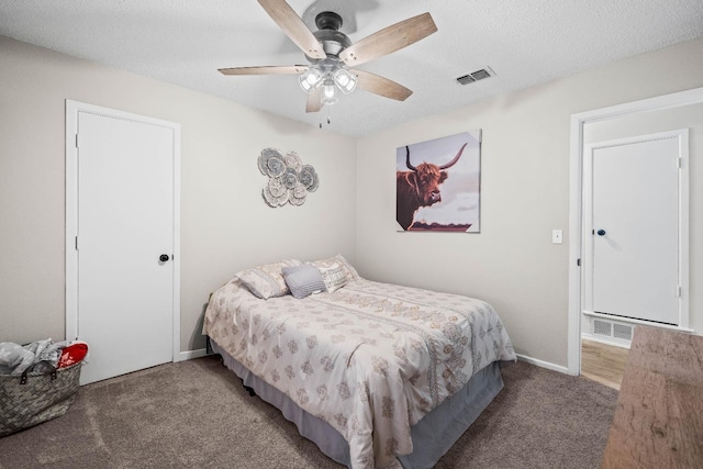 bedroom with ceiling fan, dark carpet, and a textured ceiling