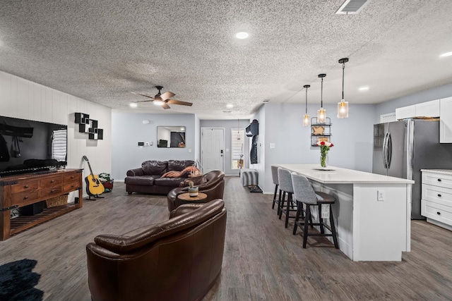 living room with ceiling fan, dark hardwood / wood-style floors, and a textured ceiling