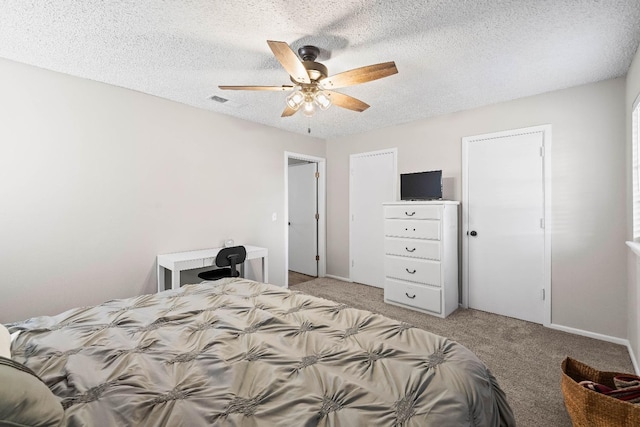 bedroom featuring ceiling fan, light colored carpet, and a textured ceiling