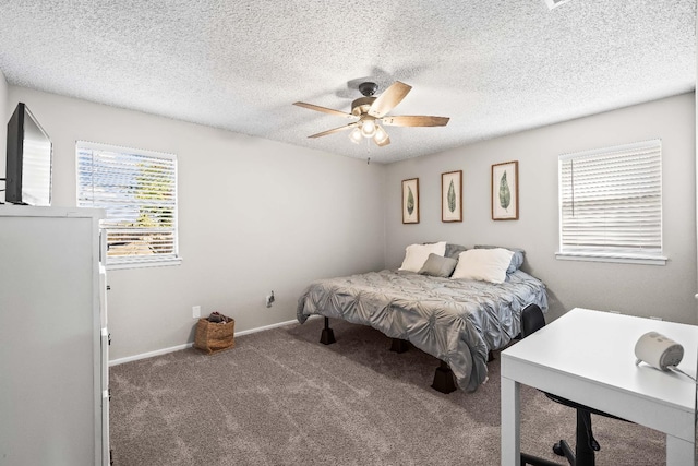 bedroom with ceiling fan, dark carpet, and a textured ceiling