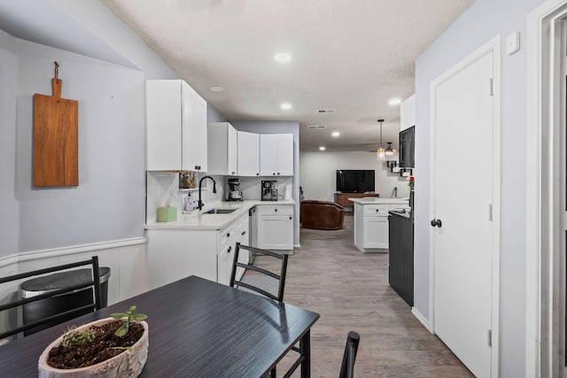 dining area featuring sink, a textured ceiling, and light hardwood / wood-style floors