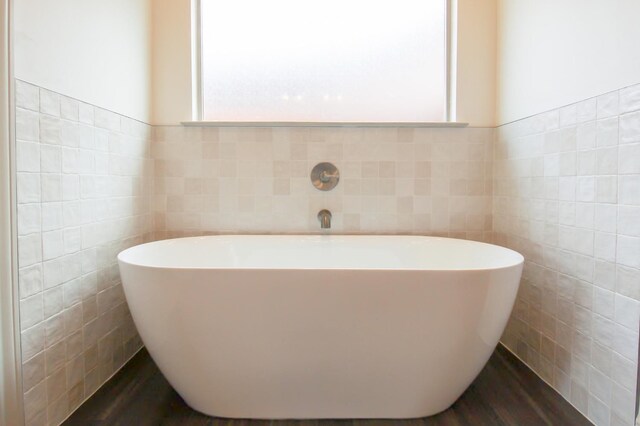 full bathroom featuring a freestanding bath, tile walls, and wood finished floors