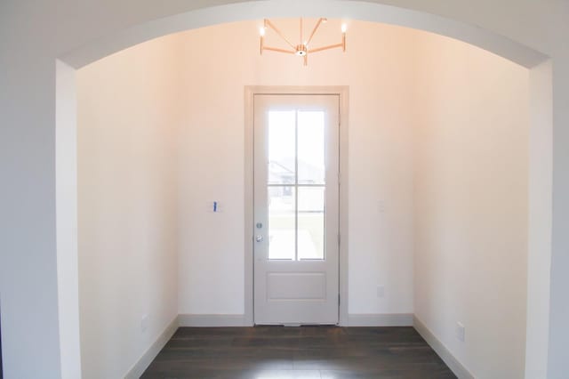 doorway featuring dark wood-style floors, baseboards, and arched walkways