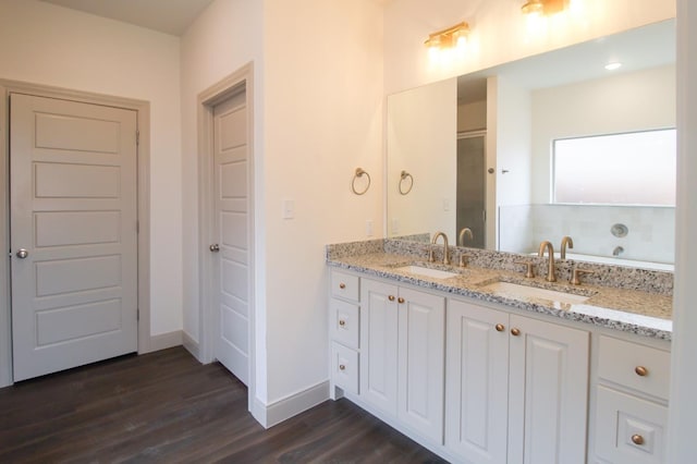 bathroom with wood finished floors, a sink, and baseboards