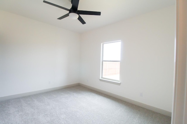 carpeted spare room featuring baseboards and a ceiling fan