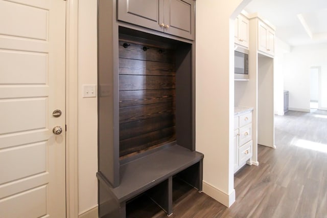 mudroom featuring arched walkways, dark wood-style flooring, and baseboards