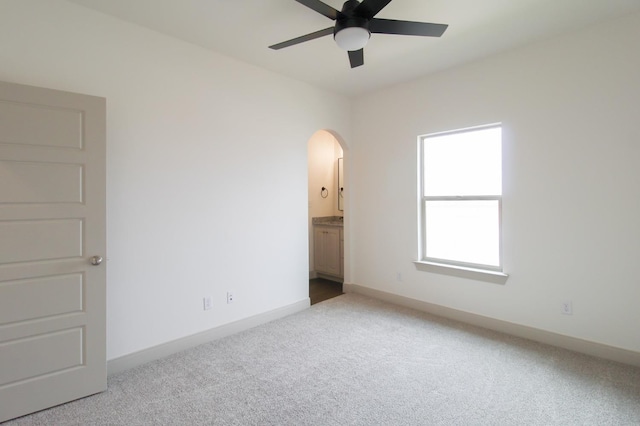 unfurnished bedroom featuring carpet floors, baseboards, and arched walkways