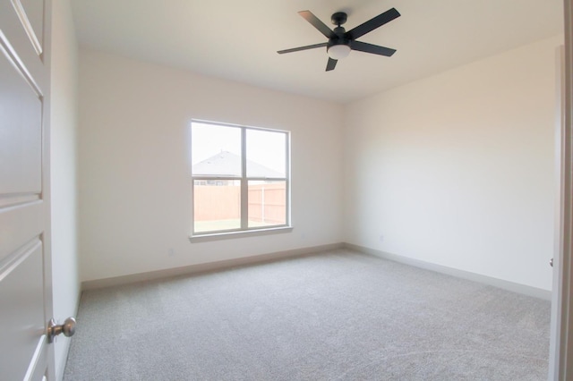 empty room with light colored carpet, ceiling fan, and baseboards