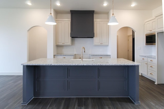 kitchen with white cabinets, arched walkways, pendant lighting, and a sink