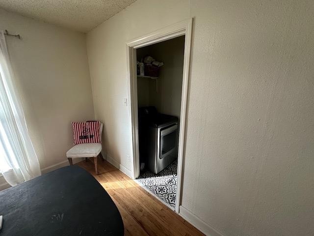 unfurnished bedroom with a walk in closet, light hardwood / wood-style flooring, a closet, and a textured ceiling