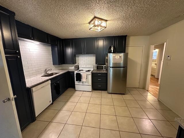 kitchen with appliances with stainless steel finishes, sink, decorative backsplash, and light tile patterned floors