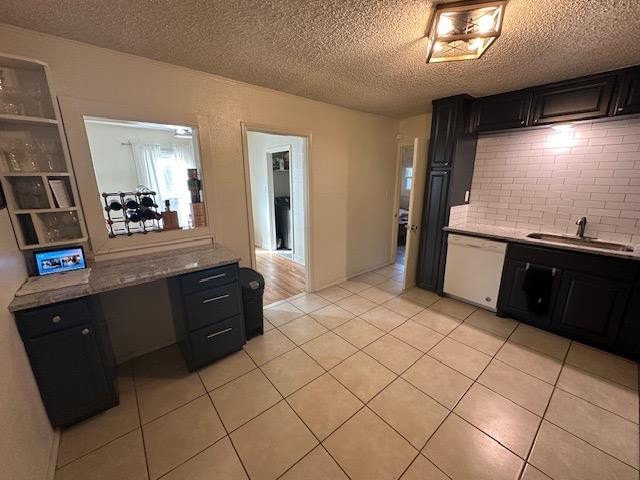 kitchen with sink, light stone counters, tasteful backsplash, light tile patterned floors, and white dishwasher