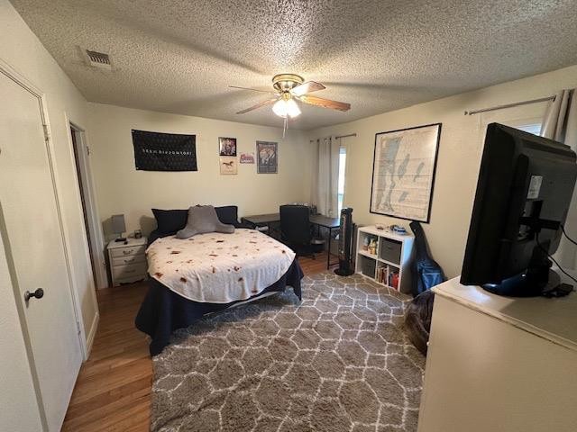 bedroom with wood-type flooring, a textured ceiling, and ceiling fan