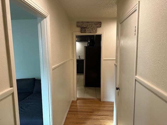 hall featuring light hardwood / wood-style floors and a textured ceiling