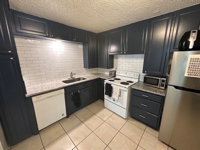 kitchen featuring sink, decorative backsplash, stainless steel appliances, and light tile patterned flooring