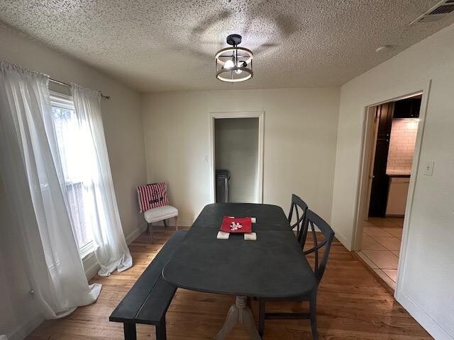 dining area with an inviting chandelier, hardwood / wood-style flooring, and a textured ceiling