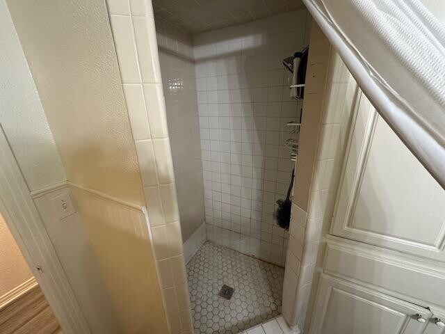 bathroom with a tile shower and hardwood / wood-style floors