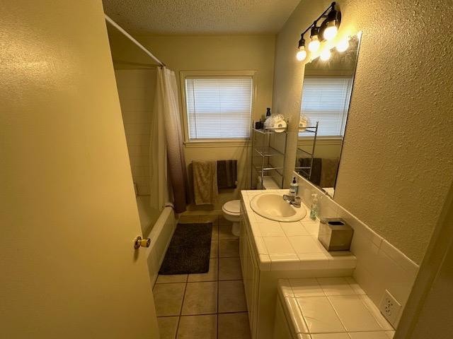 bathroom featuring tile patterned flooring, vanity, toilet, a textured ceiling, and a shower with curtain