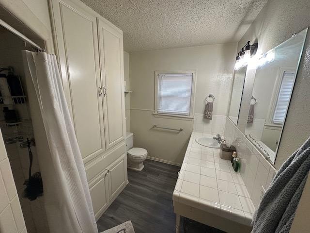 bathroom featuring vanity, toilet, hardwood / wood-style floors, and a textured ceiling