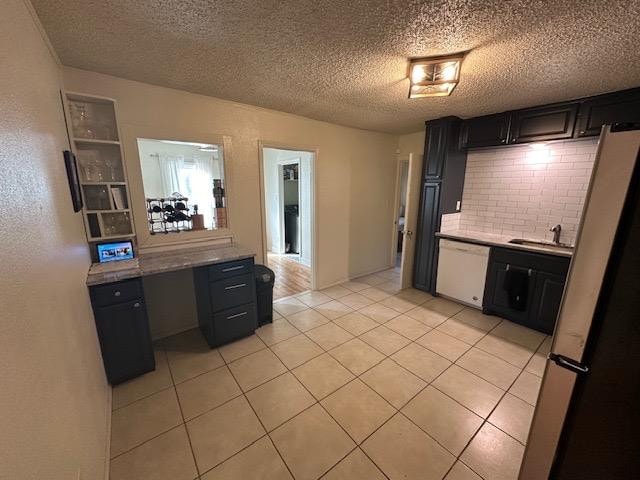 kitchen with stainless steel refrigerator, white dishwasher, light stone counters, light tile patterned flooring, and decorative backsplash