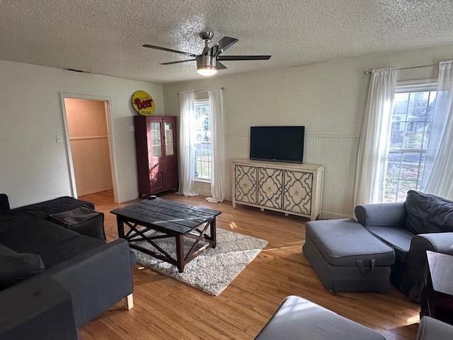 living room with hardwood / wood-style flooring, ceiling fan, plenty of natural light, and a textured ceiling