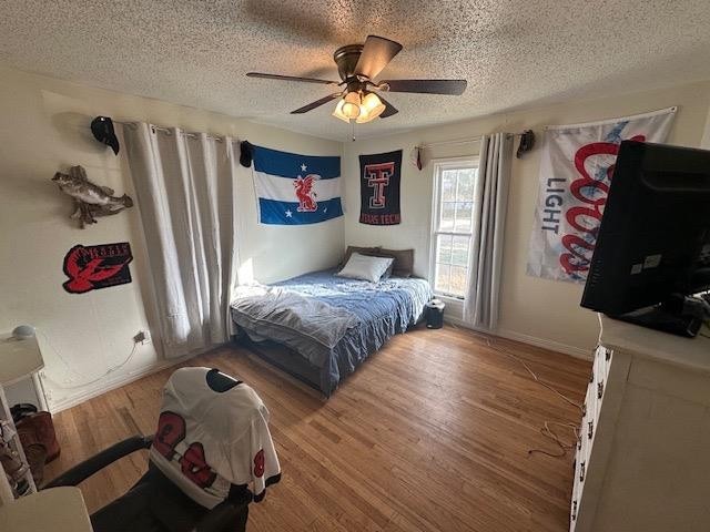 bedroom with ceiling fan, wood-type flooring, and a textured ceiling