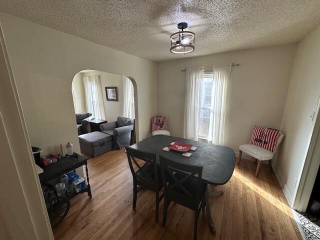 dining space with wood-type flooring and a textured ceiling