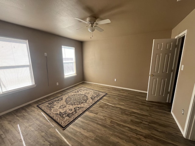 empty room with dark wood-type flooring and ceiling fan