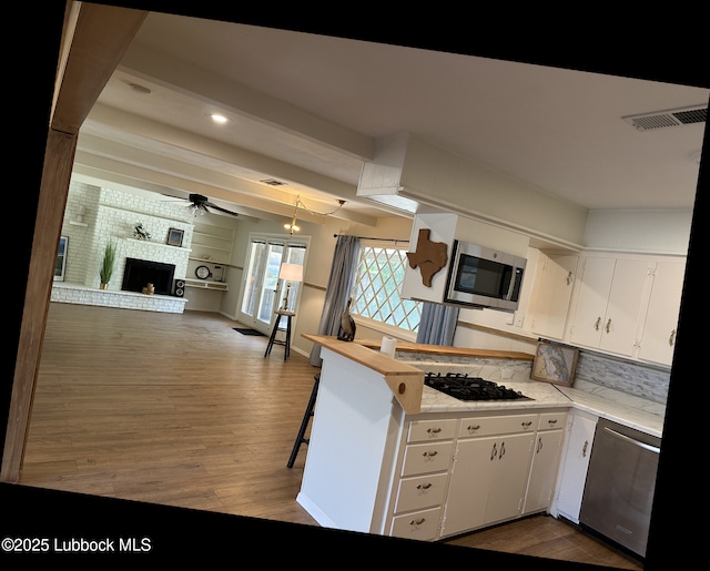 2326 58th St, Lubbock, TX 79412 - kitchen featuring appliances with stainless steel finishes, dark wood-style flooring, light countertops, white cabinetry, and ceiling fan