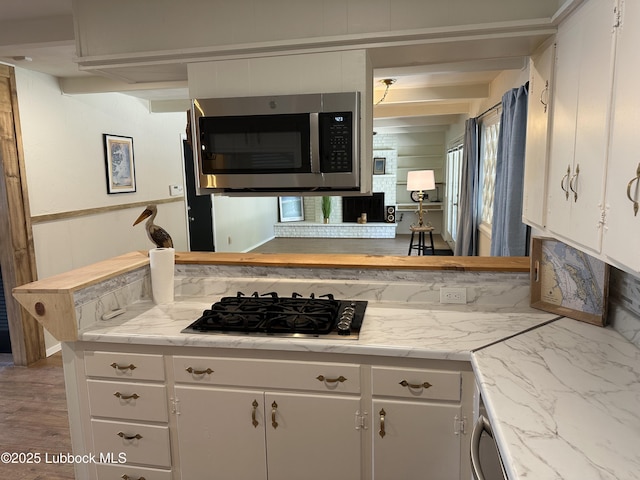 2326 58th St, Lubbock, TX 79412 - kitchen featuring stainless steel microwave, gas stovetop, and white cabinets