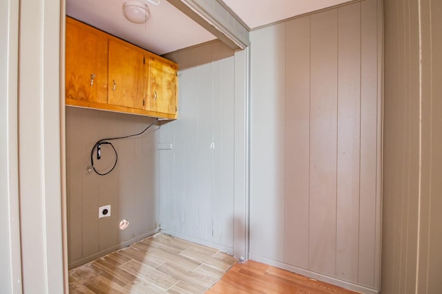 clothes washing area featuring cabinets, electric dryer hookup, and light hardwood / wood-style flooring