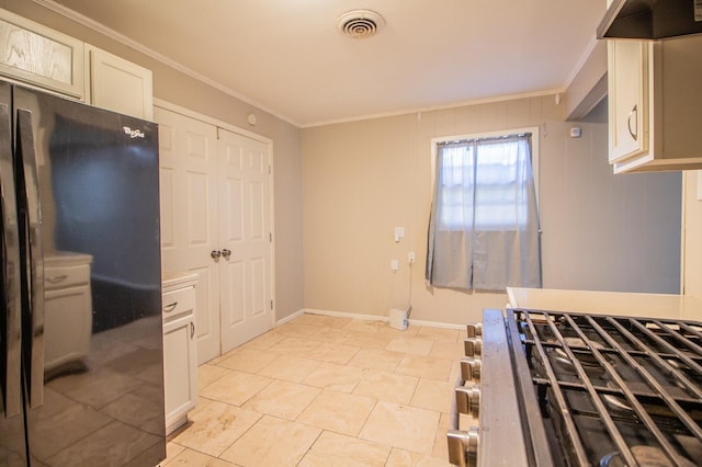 kitchen with crown molding, black fridge, white cabinets, and range hood