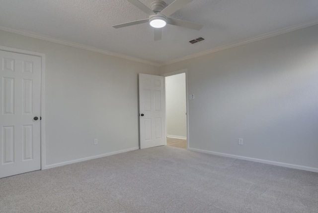 carpeted spare room featuring crown molding, ceiling fan, and a textured ceiling